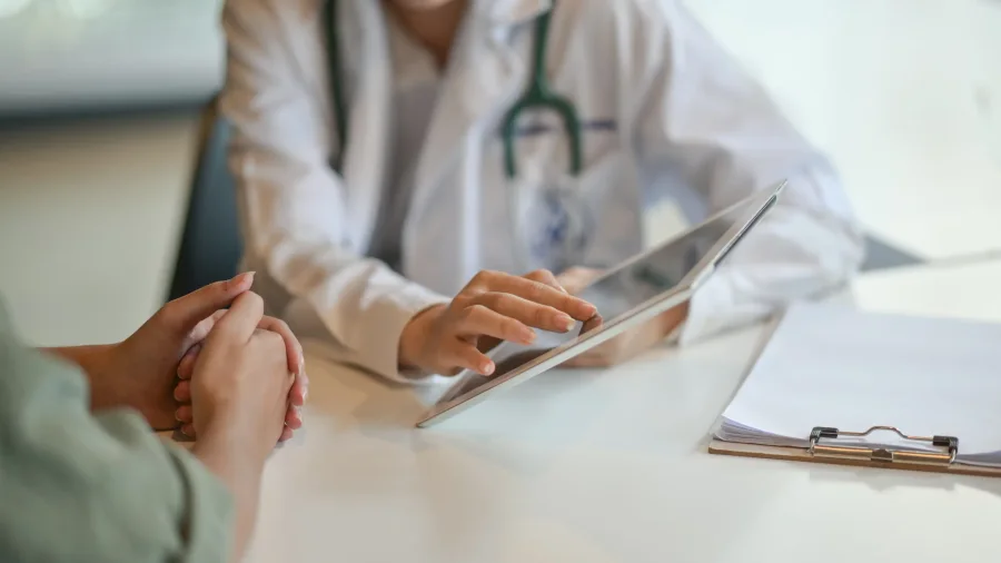 Dokter wanita menjelaskan tablet kepada pasien; ilustrasi konsultasi.