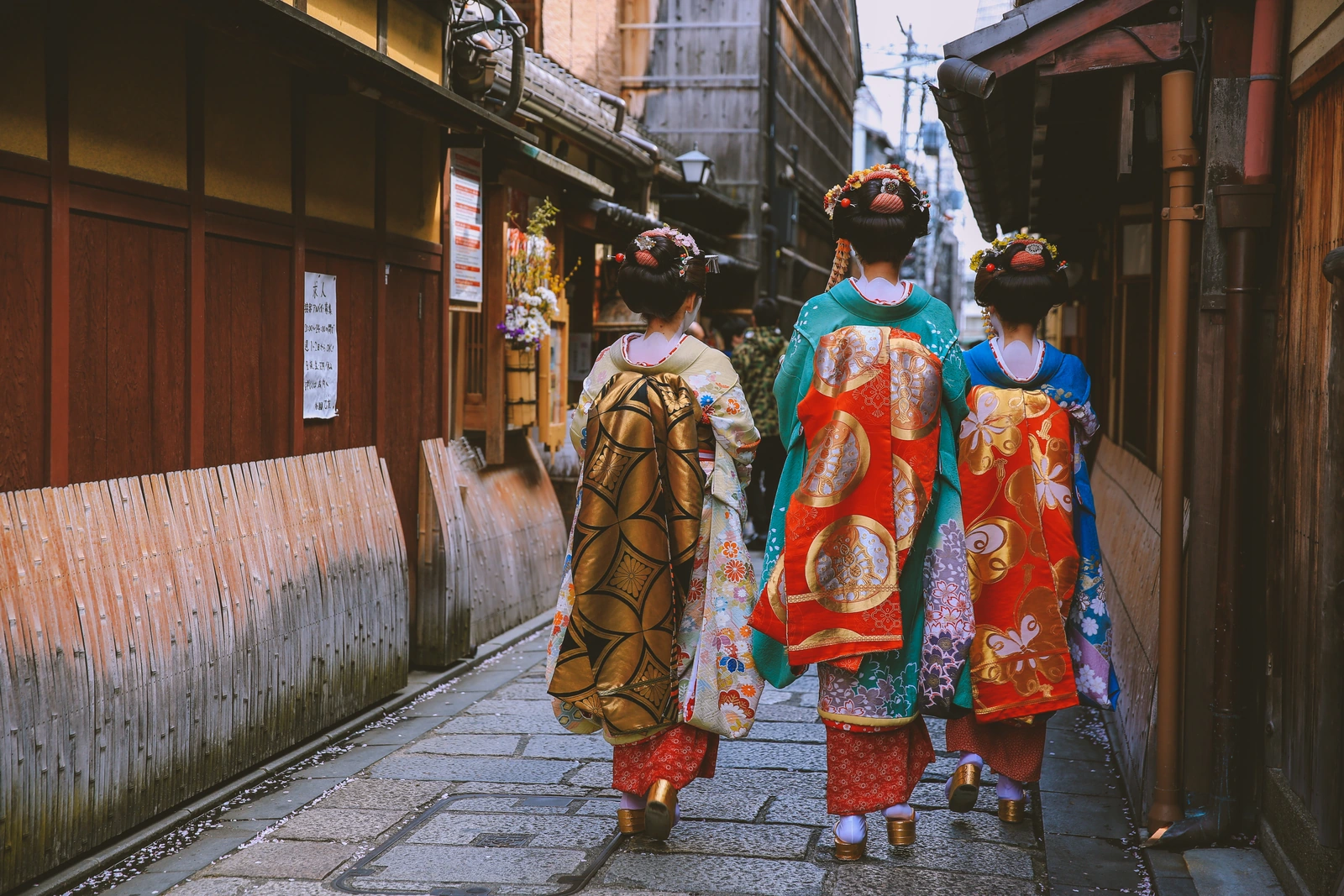 Tiga pengunjung berkimono berjalan di jalan tradisional Jepang