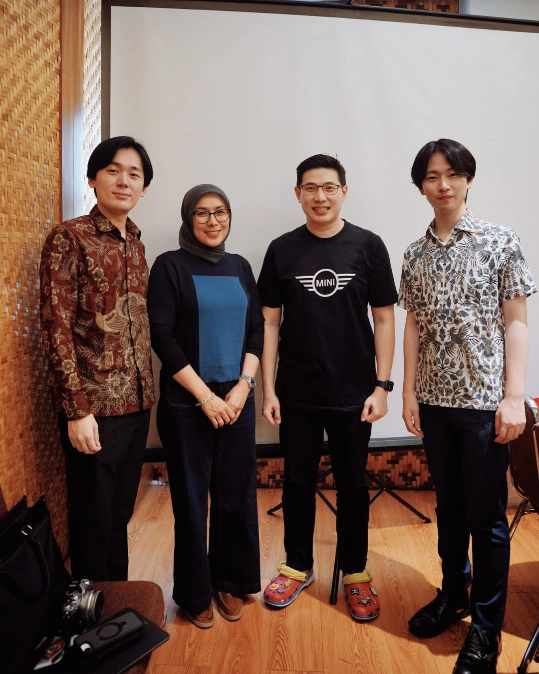 Empat orang berfoto bersama di depan layar proyeksi pada seminar IMC dan CyberGene.