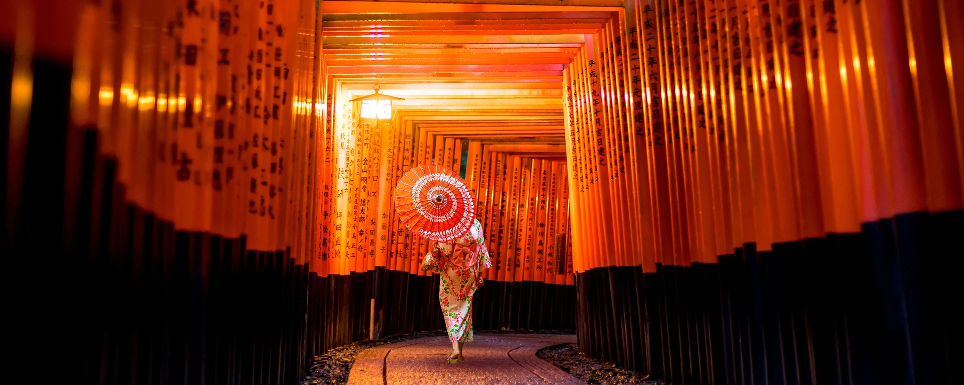 Pengunjung berjalan di bawah gerbang torii merah terang di Fushimi Inari